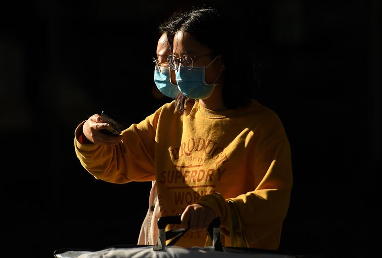 Dos mujeres con mascarilla caminan en una calle de Manchester.