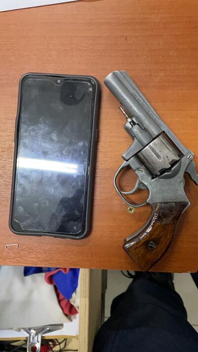 Arma de fuego y teléfono incautados de los supuestos ladrones.