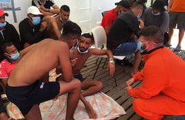 Un rescatista habla con migrantes en el barco "Ocean Viking", luego de que dos de ellos saltaran por la borda en el mar Mediterráneo y fueran rescatados.