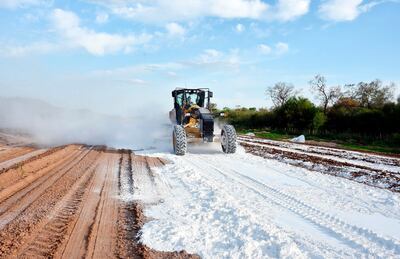 Maquinaria vial distribuye cal viva en el suelo, como parte de los preparativos para la instalación de la capa asfáltica. La cal ayuda a la compactación del suelo y control de la humedad.