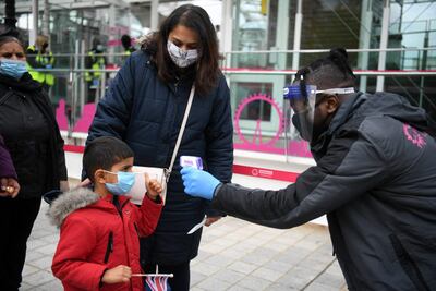 Un trabajador toma la temperatura de los clientes mientras hacen cola para abordar una cápsula en la atracción turística reabierta del London Eye, en Londres.