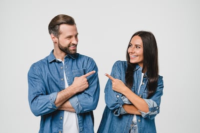 Un hombre y una mujer jóvenes se señalan uno a otro entre sí