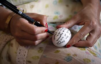 Una mujer escribe su mensaje en un huevo durante la peregrinación anual a El Ghriba, para conmemorar el día sagrado de Lag B'Omer.