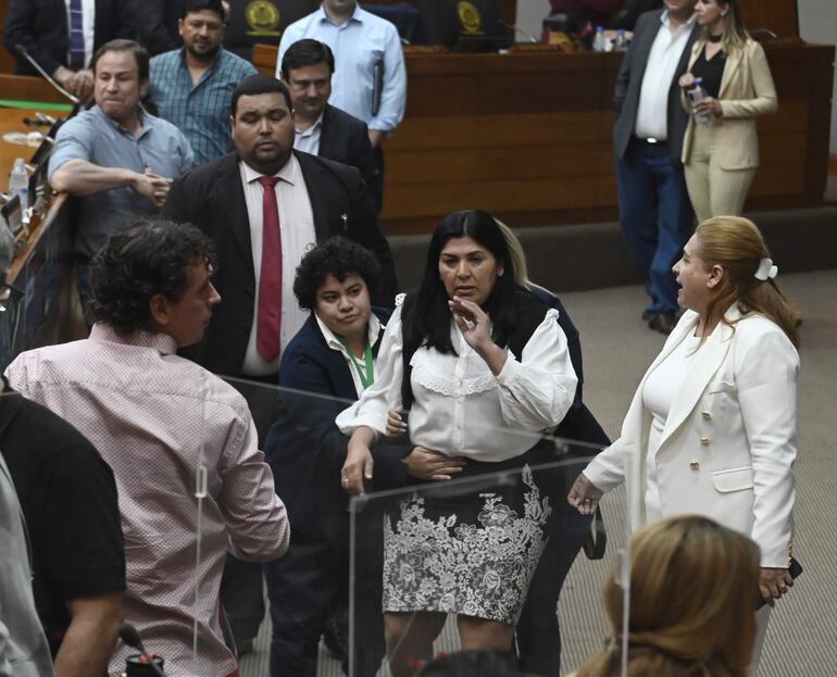 La diputada cartista Del Pilar Medina fuera de sí es sujetada por una funcionaria en la sala de sesiones de Diputados, tras levantarse la sesión de diputados por desorden en la sala. La misma a los gritos trataba de coimera y compra bancas a Amarilla.