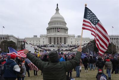 Un seguidor de Donald Trump sostiene la bandera de los Estados Unidos, frente al Capitolio.