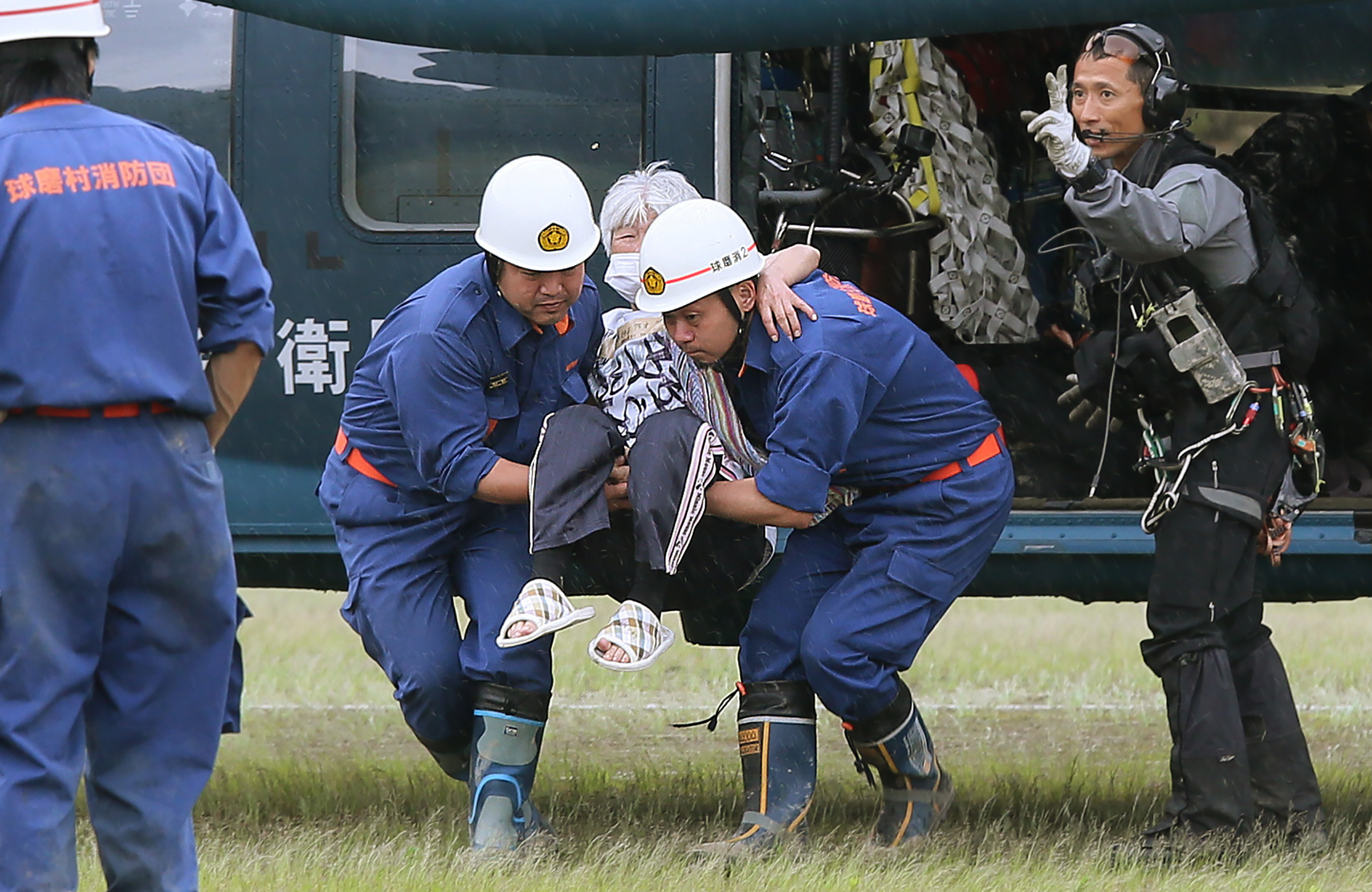 Bomberos de la localidad de Kuma llevan a una mujer de avanzada edad que fue evacuada por militares de la zona de inundaciones en la prefectura japonesa de Kumamoto.