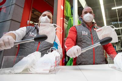 Empleados de un supermercado en Viena, Austria, utilizan pinzas para entregar tapabocas FFP2 a sus clientes.