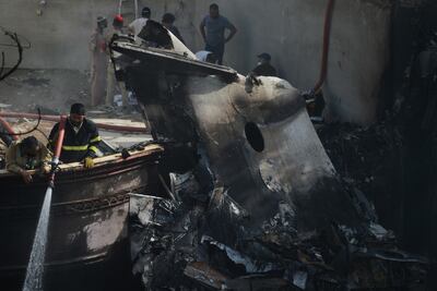 Un bombero rocía agua sobre los restos del avión que cayó en una zona residencial de Karachi, Pakistán.