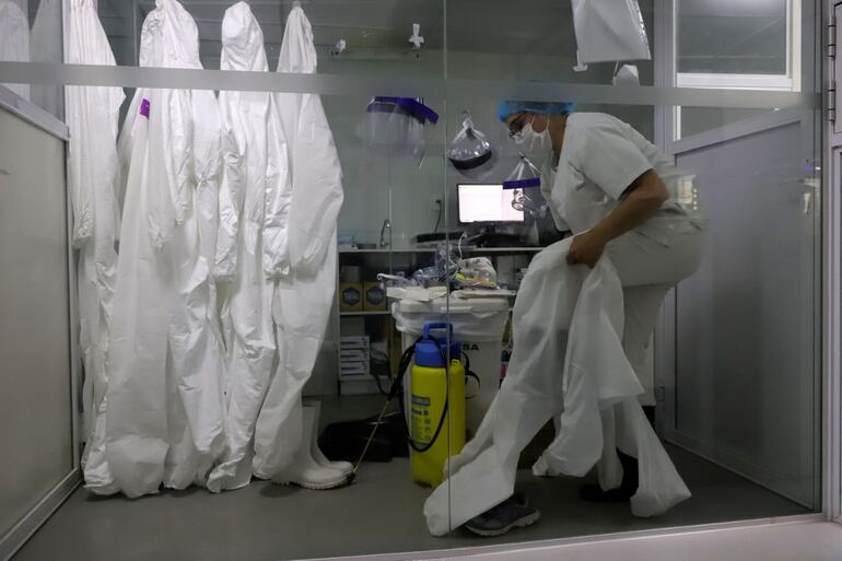 Un profesional de la salud inicia el proceso de enfundarse en un traje de protección para ingresar a la Unidad de Terapia Intensiva (UTI) del Instituto Nacional de Enfermedades Respiratorias y del Ambiente Juan Max Boettner (Ineram), donde están internados pacientes con Covid-19 (coronavirus).