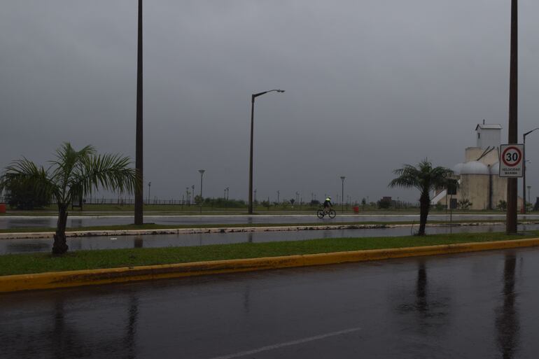 Un ciclista desafía a la llovizna y recorre la avenida costanera de Encarnación.