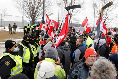 La policía canadiense observa a los manifestantes contra la obligatoriedad de la vacunación contra el covid-19, mientras bloquean la entrada al puente Ambassador en Windsor, Ontario.
