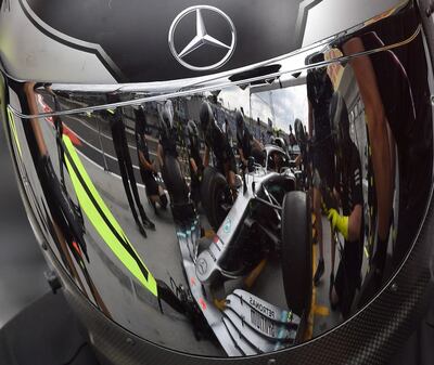 La pantalla plateada de un casco de carreras refleja a los técnicos del equipo Mercedes trabajando antes de la pandemia.