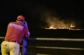 Bomberos apostados en la costanera veridican desde lejos las labores de sus camaradas en combate a las llamas.
