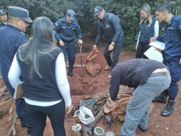 Miembros de la comitiva fiscal policial proceden a retirar varias de las piezas que estaban escondidas bajo tierra en el predio de una de las viviendas allanadas.