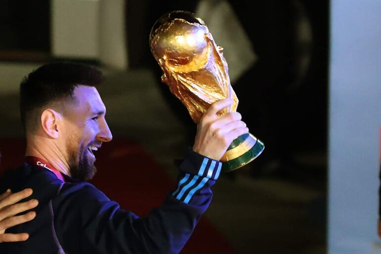 Lionel Messi bajando del avión con la Copa del Mundo en mano en el regreso de Argentina después de conquistar el Mundial Qatar 2022. 