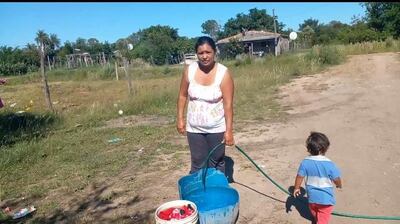 Una mujer del barrio Ytororo de Pilar, junta agua en un recipiente, clama por la instalación del servicio de agua potable de Essap.