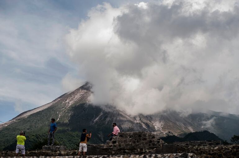 Varias personas observan una erupción del volcán del monte Merapi, en Indonesia.