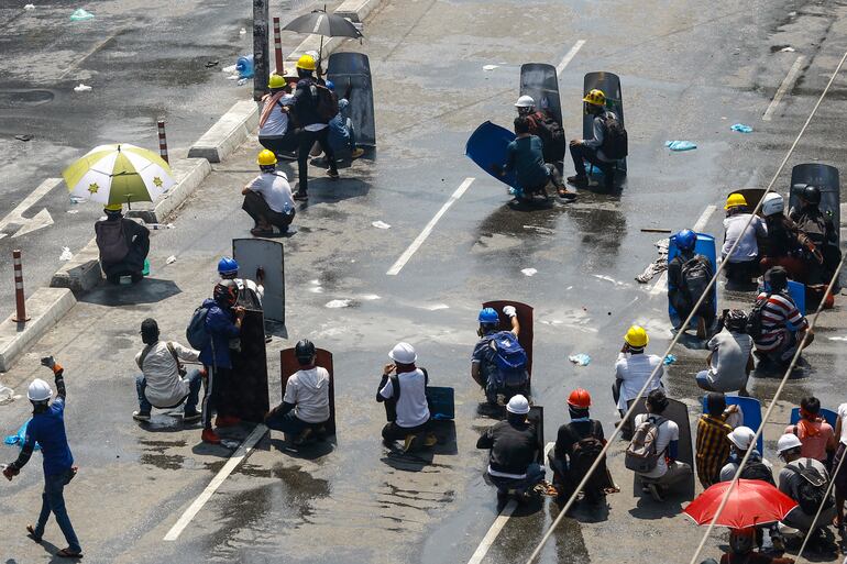 Manifestantes se protegen con escudos caseros durante una protesta contra el golpe militar, en Rangún, este lunes.
