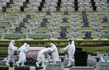 Personas en trajes protectores llevan un ataúd de una persona que murió con COVID-19 en un cementerio en Setia Alam, en las afueras de Kuala Lumpur, Malasia.