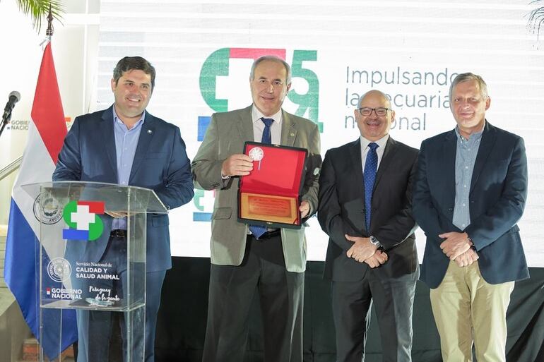 Homenaje al titular de la Organización Mundial de Salud Animal (OIE), doctor Hugo Idoyaga, en la Expo 2021, mostrando la placa entregada por el Senacsa, como homenaje por elevar al Paraguay en el más alto cargo mundial de la sanidad pecuaria. Le acompañan el vicecanciller, Raúl Cano Ricciardi y el ministro de Agricultura y Ganadería, ingeniero Santiago Bertoni, además del titular del ente, José Carlos Martin.