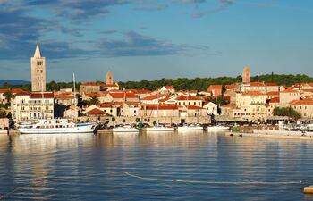 De repente, se abre la vista. A través de las hojas y las ramas, se hace visible el verde del bosque que desciende hacia la costa. La vegetación, exuberante para el Adriático, es una marca registrada de Rab.
