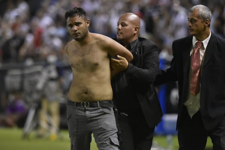 El hincha de Guaraní que ingresó al campo es sujetado y retirado por la seguridad privada de La Huerta.