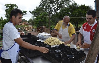 Isabelino Trinidad (remera amarilla) elabora panes dulces con ayuda de su familia.