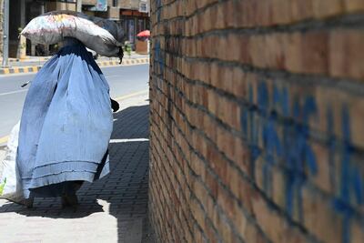 Una mujer tapada con un burka y una bolsa en la cabeza camina por las calles de Kabul.