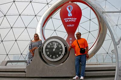 Dos turistas posan en Doha junto al reloj que marca la cuenta regresiva para el Mundial de Qatar, cuyo inicio podría adelantarse un día, para el 20 de noviembre.
