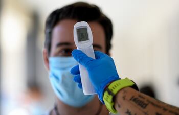 Un trabajador sanitario le toma la temperatura a un hombre en un centro de pruebas temporal para el nuevo coronavirus en Madrid.