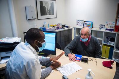 Un hombre habla con su médico antes de recibir la primera dosis de la vacuna de Oxford Astra-Zeneca en un consultorio en París.