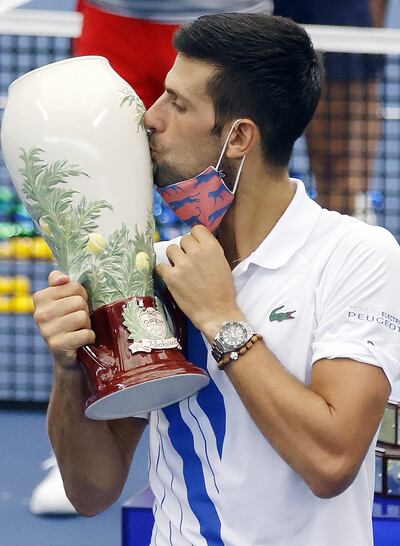 El serbio Novak Djokovic se quita el tapabocas para besar el trofeo con el que se hizo tras vencer a Milos Raonic. Foto: EFE.