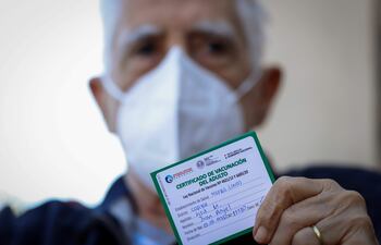 Un adulto mayor muestra su certificado de vacunación tras recibir una dosis de vacuna contra el COVID-19 hoy, en la sede de la Secretaría Nacional de Deportes (SND).