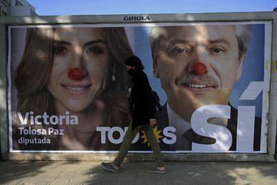 Una mujer camina junto a un mural vandalizado con publicidad del Frente de Todos con el rostro del presidente argentino Alberto Fernández y la candidata a diputada de la provincia de Buenos Aires Victoria Tolosa Paz.