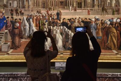 Visitantes toman fotos de la pintura 'San Marcos predicando en Alejandría' de Gentile y Giovanni Bellini, exhibida en la prestigiosa galería de arte Pinacoteca di Brera en Italia.