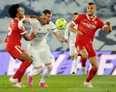 Karim Benzema (c) pelea por el balón con dos jugadores del Sevilla, Jules Kounde  y  Joan Jordan Moreno. (AFP)