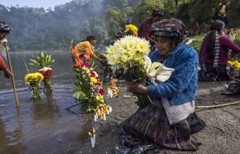 Indígenas participan en una ceremonia en la que, con ofrendas florales, agradecen a la naturaleza por la lluvia, hoy, en la laguna de Chicabal (Guatemala). Esta laguna, considerada sagrada por el pueblo maya mam, está asentada en el cráter del volcán Chicabal a 2.000 metros de altura sobre el nivel del mar y se ubica en el departamento (provincia) de Quetzaltenango, 220 kilómetros al oeste de la Ciudad de Guatemala. Esta costumbre, con cientos de años de historia, es considerada por los guías espirituales mayas como una ceremonia que conecta a los creyentes con la naturaleza y sus ancestros.