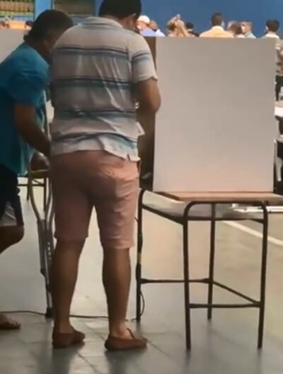 Momento en que supuestamente este hombre de camisa a rayas tomaba una fotografía al voto del hombre de remera azul.
