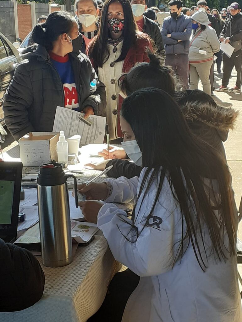 Una funcionaria asignada el sector de registro de pacientes con un guardapolvos donde lleva el distintivo de campaña del candidato colorado a la intendencia de Encarnación, César Rojas.