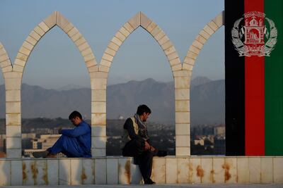 Dos hombres sentados junto a una bandera de Afganistán en Kabul.