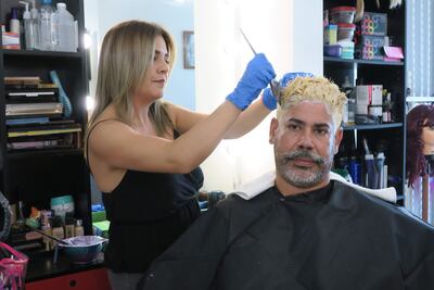 USA5020. DORADO (PUERTO RICO), 10/03/2023.- La estilista Haydeliz Cruz pinta de rubio la cabellera de Carlos Miranda, que decidió cambiar de color su cabello en respaldo al "Team Rubio", el 8 de marzo de 2023, en su residencia en Dorado (Puerto Rico). Los aficionados al béisbol en Puerto Rico vuelven estos días a unirse a la moda de teñirse sus cabellos de rubio en apoyo a la selección que compite desde este sábado en la quinta edición del Clásico Mundial de Béisbol. EFE/ Jorge Muñiz