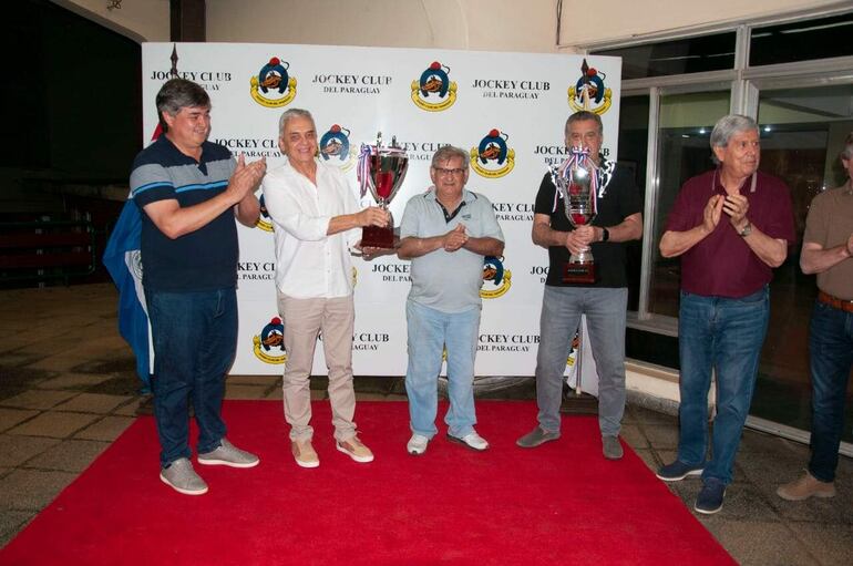 Julio López (2° izq.) acompañado del cuidador Carlos Alcaraz (3°) recibió la copa en el Premio Especial “Socios Fundadores”, en representación de Roberto Antebi. El pingo Sr Api ganó el premio  “Socios Fundadores del Jockey Club del Paraguay”.