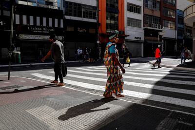 Personas con tapabocas caminan frente a tiendas cerradas por la situación del coronavirus, en la ciudad de Sao Paulo (Brasil). Varias ciudades de los estados brasileños de Sao Paulo, Ceará, Amazonas y Pará, cuatro de los más azotados por la crisis de coronavirus, iniciaron ayer la reapertura gradual de sus economías.