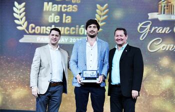 Lic. Julio Mendoza (i), presidente de la Cámara Paraguaya de Consultores, entrega el premio a los ingenieros Juan Villasanti (centro) y José Luis Vinader Ashwell de BH Concretos.