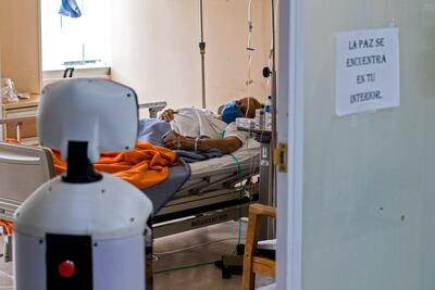 LaLuchy Robotina se para en la puerta de una sala de internación, próxima a un paciente con Covid, en el Centro Médico Nacional de México.