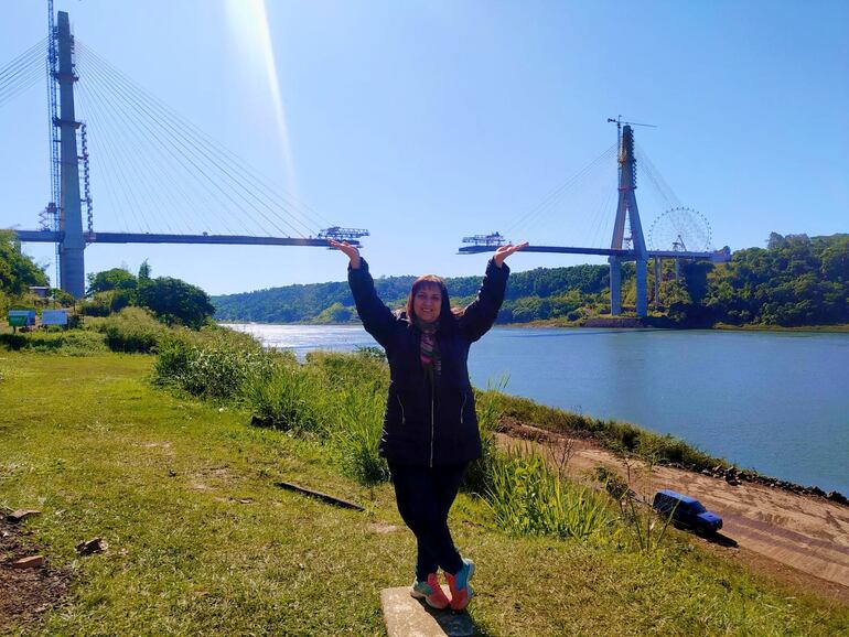 Una pobladora extiende sus manos sobre ambos extremos del puente que están a punto de unirse.