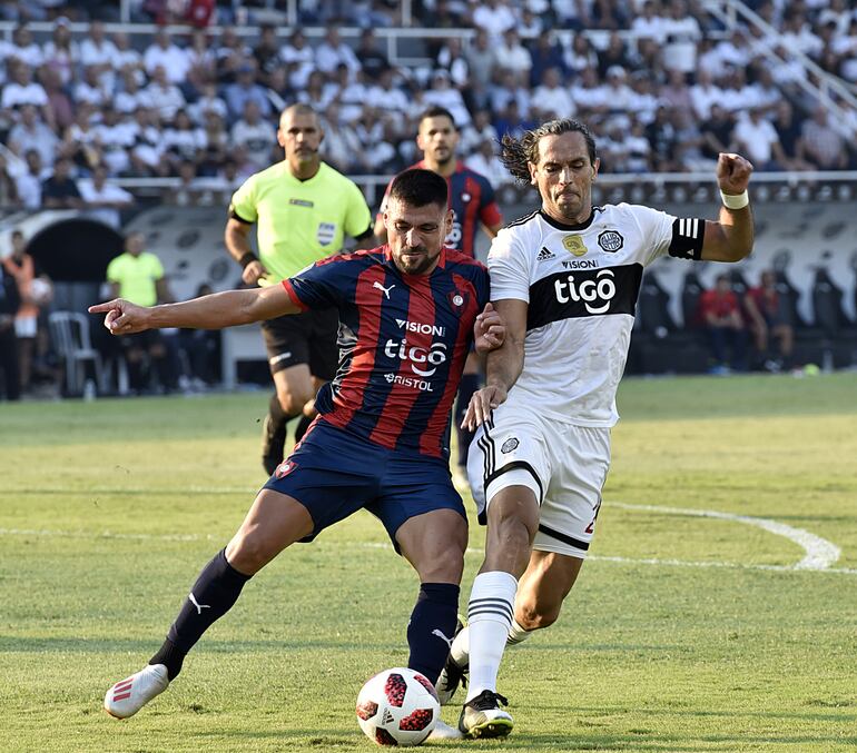 Roque Santa Cruz, quien solo jugó el primer tiempo del clásico frente  a Cerro Porteño, en dura puja por la pelota  con el defensor azulgrana Juan Patiño. En reemplazo del capitán olimpista ingresó en su primer partido con la casaca franjeada el jugador togolés Emmanuel Adebayor, que estuvo cerca de anotar con un cabezazo.