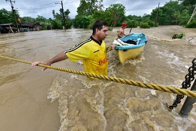 Dos personas tratan de cruzar una zona inundada por el desborde de los ríos hoy, en la sierra de Tabasco (México). Las lluvias del ciclón Eta y el frente frío número 11 han dejado al menos 80.000 afectados y 12 muertes hasta este viernes en el sureste mexicano, dos por ahogamiento en Tabasco y el resto por derrumbes en Chiapas.
