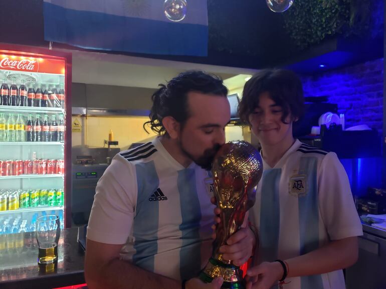 Tomás y Santino Centurión besando la Copa del Mundo que obtuvo Argentina en el Mundial de Catar.