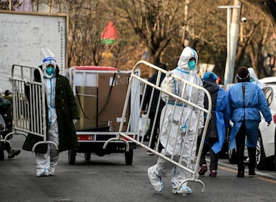 Trabajadores de la salud transportan vallas en una zona de Pekín reabierta luego de una cuarentena.